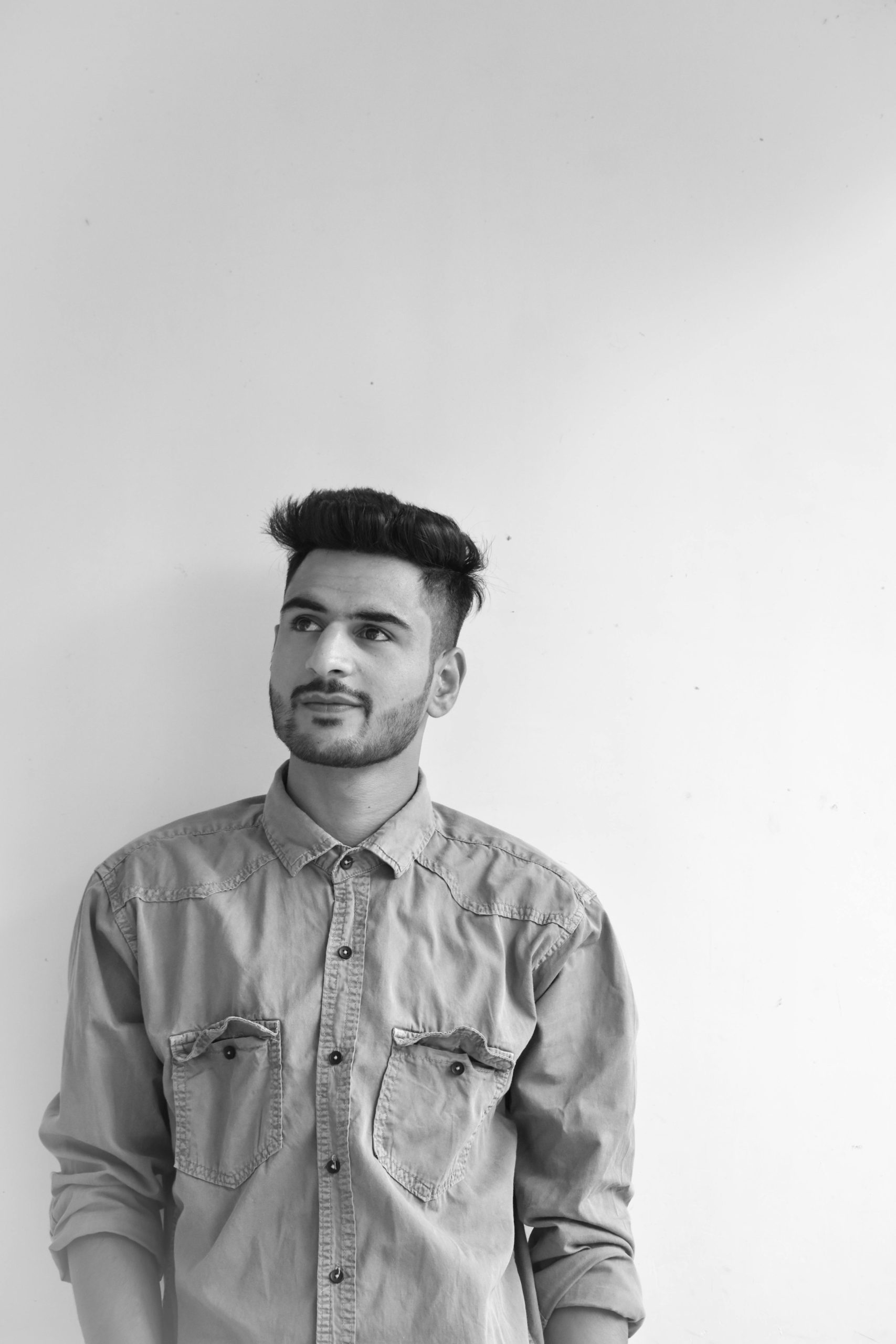Black and white portrait of a handsome young man looking away wearing a denim shirt.