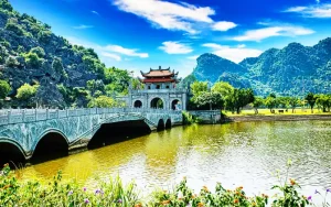 Stone bridge leading to Hoa Lu Ancient Capital in Ninh Binh surrounded by mountains.