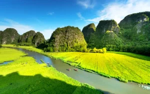 Tourists sitting on a traditional rowing boat during the scenic Tam Coc boat tour in Ninh Binh