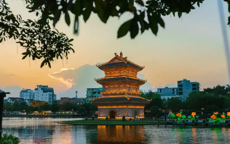 The illuminated Tu An Tower reflecting on Ky Lan Lake at Hoa Lu Ancient Town in Ninh Binh Vietnam at night